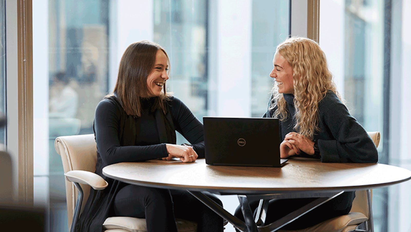 Two women smiling and in discussion over a laptop