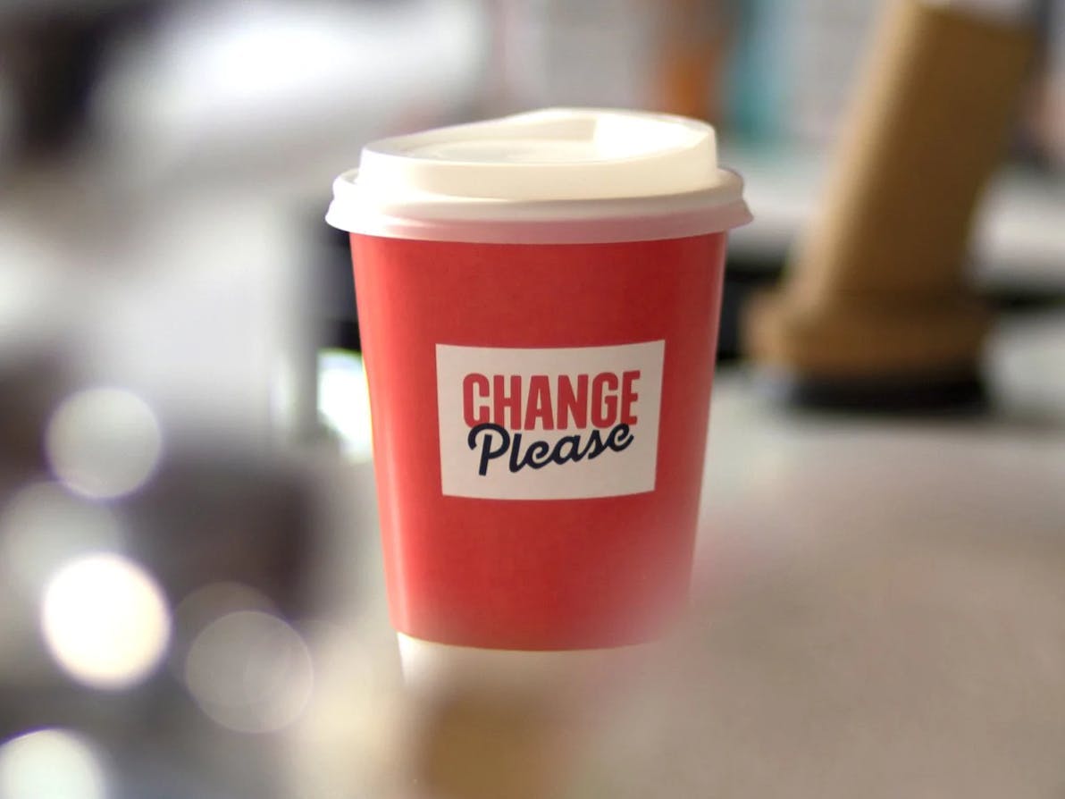 a coffee cup bearing the change please logo
